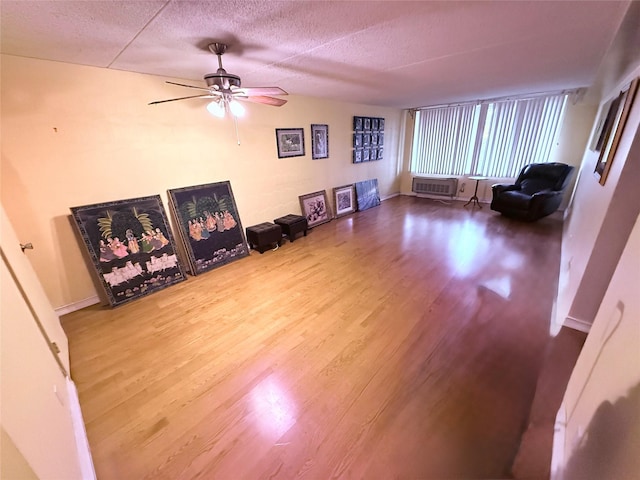 20921 26th Ave Unit 1G, Bayside, NY 11360 - living area featuring a textured ceiling, wood finished floors, ceiling fan, and a wall unit AC