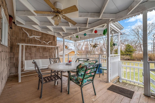 sunroom featuring outdoor dining area, a ceiling fan, and beamed ceiling