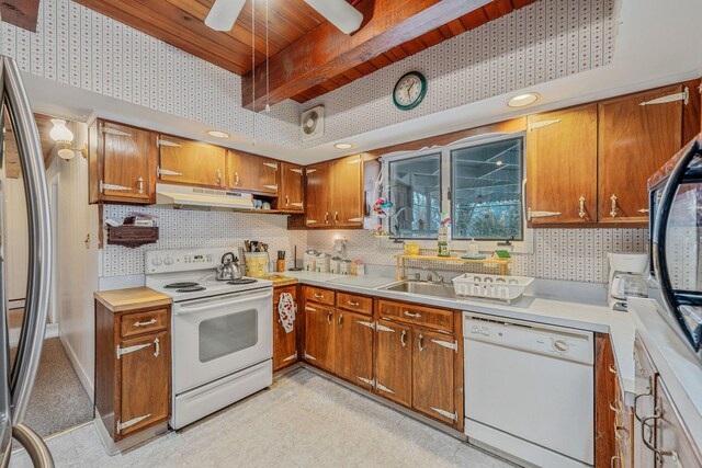 kitchen with light countertops, brown cabinets, under cabinet range hood, and white appliances