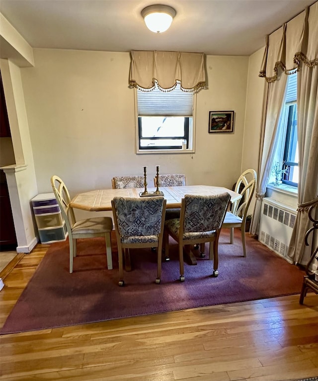 dining area with radiator heating unit and light wood-style floors