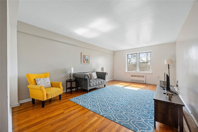 living area with light wood-style flooring, radiator heating unit, and baseboards