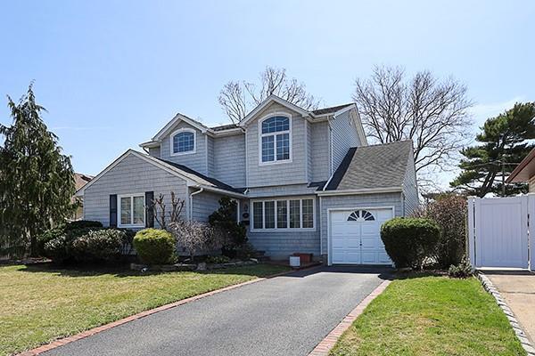traditional home with an attached garage, aphalt driveway, a front yard, and a gate