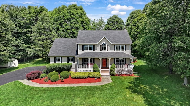 34 Melissa Ln, Washingtonville, NY 10992 - colonial home featuring covered porch, a front yard, a shingled roof, asphalt driveway, and a shed
