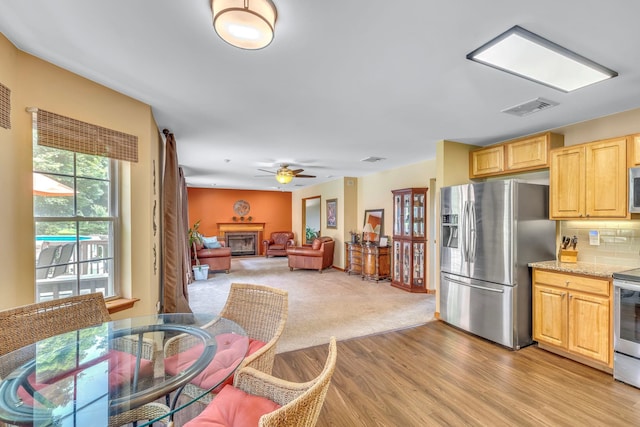 34 Melissa Ln, Washingtonville, NY 10992 - kitchen featuring stainless steel appliances, tasteful backsplash, a ceiling fan, a glass covered fireplace, and light brown cabinets
