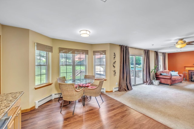 34 Melissa Ln, Washingtonville, NY 10992 - dining area with baseboard heating, light wood-style flooring, a glass covered fireplace, and ceiling fan