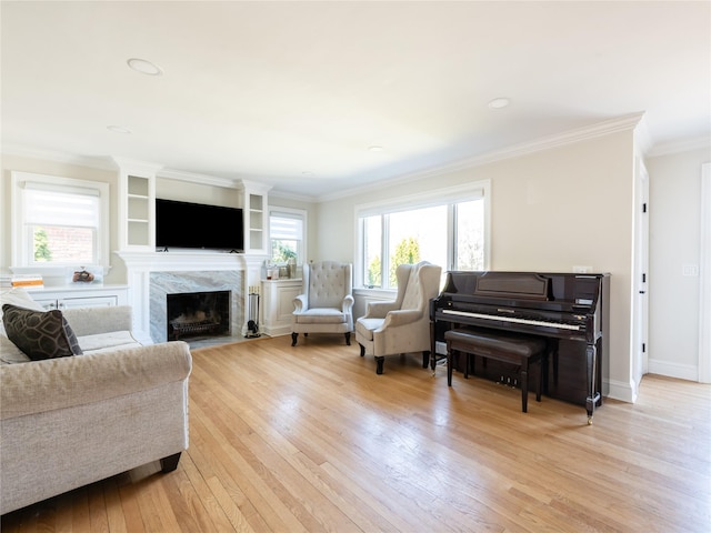 living area featuring light wood-style flooring, crown molding, baseboards, and a fireplace