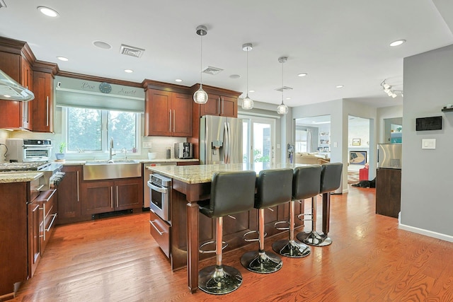kitchen featuring a sink, a breakfast bar, stainless steel appliances, a center island, and backsplash