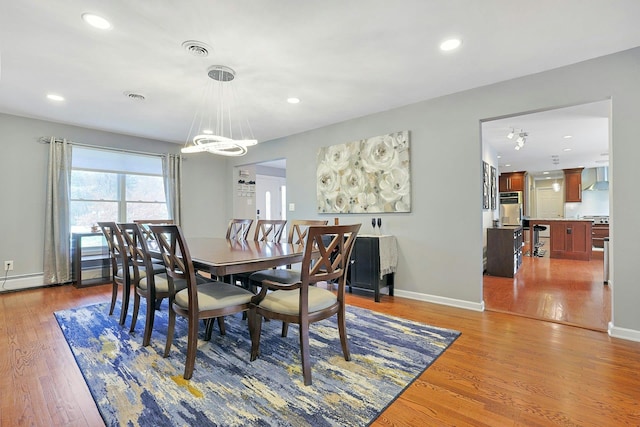 dining room with an inviting chandelier, wood finished floors, recessed lighting, and baseboards