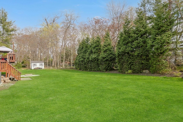 view of yard with an outdoor structure, a storage shed, and stairs