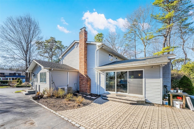 1170 Carlls Straight Path, Dix Hills, NY 11746 - back of property with entry steps, aphalt driveway, and a chimney