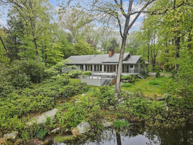 back of property with a chimney and covered porch
