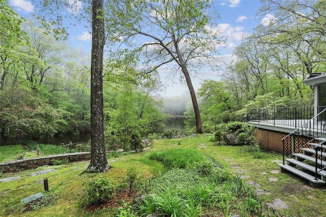 view of yard featuring a deck with water view and stairs
