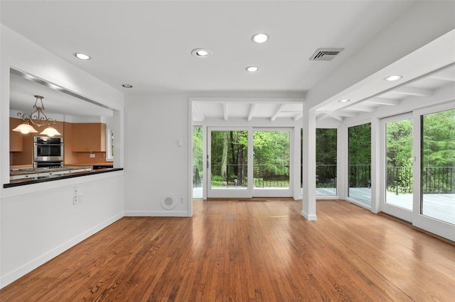 unfurnished living room with wood finished floors, recessed lighting, beamed ceiling, and baseboards