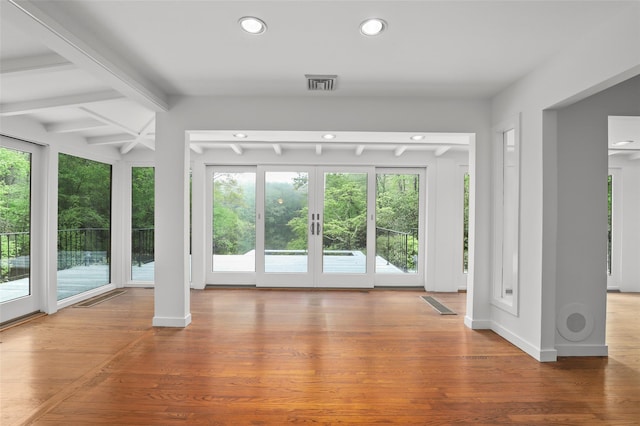 unfurnished sunroom featuring french doors, plenty of natural light, and beamed ceiling