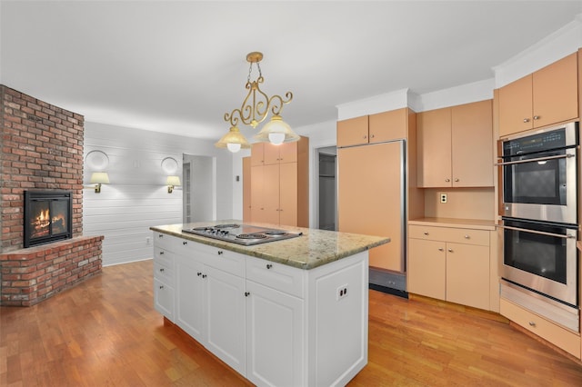kitchen with stainless steel appliances, light wood-style floors, a fireplace, hanging light fixtures, and a center island