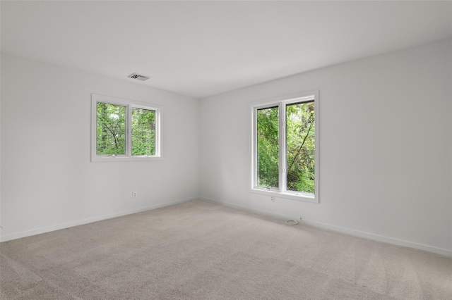 unfurnished room featuring plenty of natural light, baseboards, and light carpet