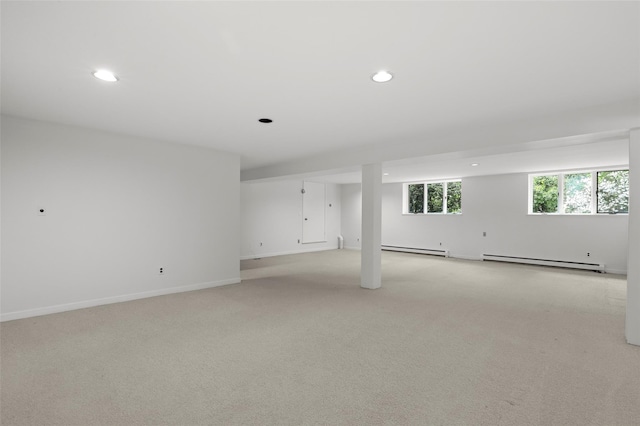 spare room with a baseboard heating unit, light colored carpet, recessed lighting, baseboard heating, and baseboards