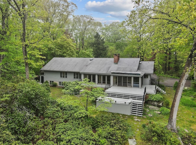 rear view of property featuring stairway, a chimney, a wooden deck, and a sunroom