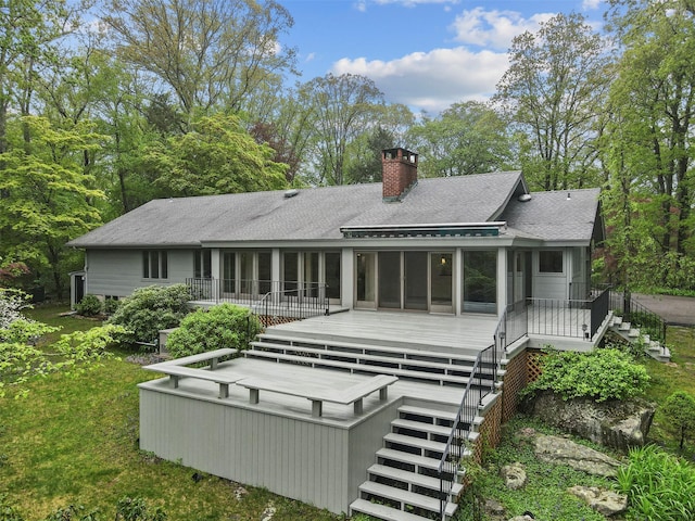 back of property with stairway, a sunroom, a chimney, and a shingled roof