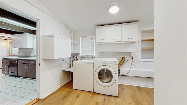 laundry room featuring washing machine and clothes dryer, baseboards, light wood finished floors, and cabinet space