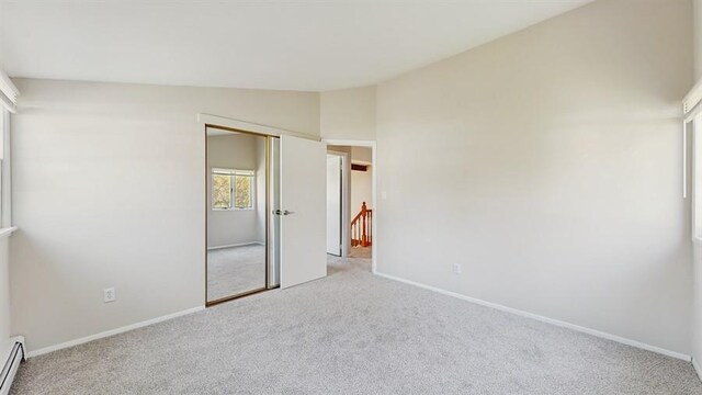 unfurnished bedroom featuring baseboards, lofted ceiling, and carpet