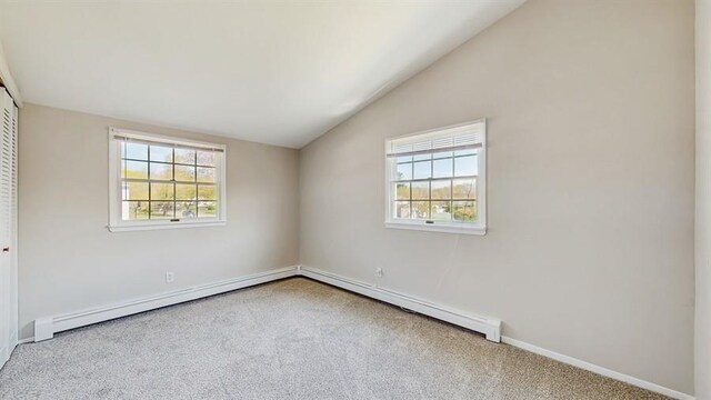 carpeted spare room featuring a baseboard radiator, lofted ceiling, and baseboards