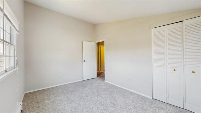 unfurnished bedroom featuring baseboards, carpet flooring, and a closet
