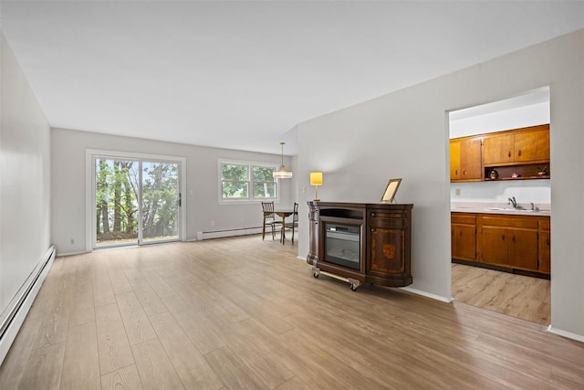 75 Vails Gate Heights Dr, Vails Gate, NY 12553 - unfurnished living room with a baseboard radiator, light wood-type flooring, a sink, and baseboards