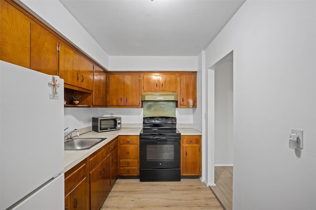 75 Vails Gate Heights Dr, Vails Gate, NY 12553 - kitchen featuring freestanding refrigerator, black electric range oven, a sink, under cabinet range hood, and light wood finished floors