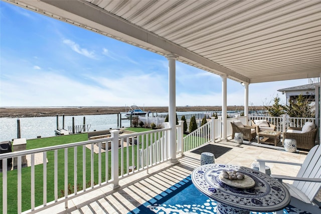 deck featuring an outdoor hangout area, a water view, boat lift, a dock, and a lawn