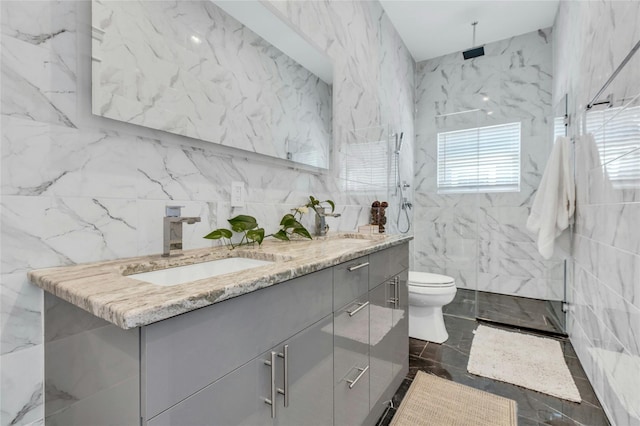 bathroom featuring tile walls, double vanity, a sink, and a marble finish shower