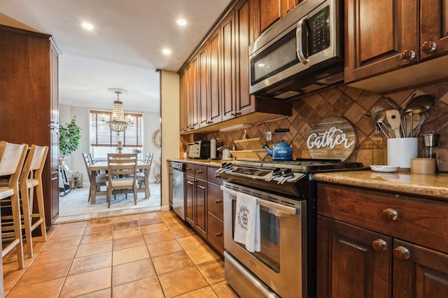 700 Shore Rd Unit 2Z, Long Beach, NY 11561 - kitchen with decorative backsplash, baseboards, appliances with stainless steel finishes, an inviting chandelier, and light tile patterned floors