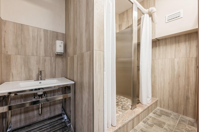 700 Shore Rd Unit 2Z, Long Beach, NY 11561 - bathroom with a shower stall, stone finish floor, visible vents, and tile walls