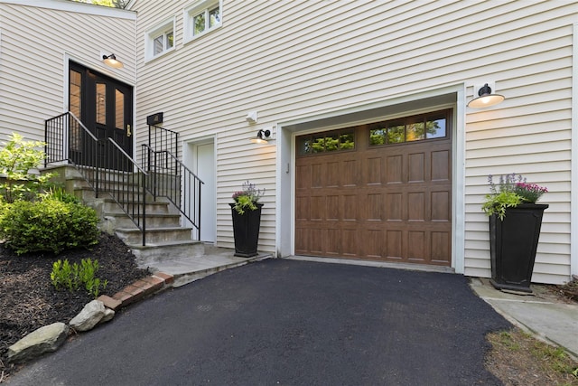 view of exterior entry with an attached garage and driveway
