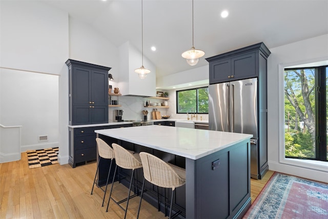 kitchen featuring open shelves, light wood-type flooring, a kitchen island, a breakfast bar, and light stone counters