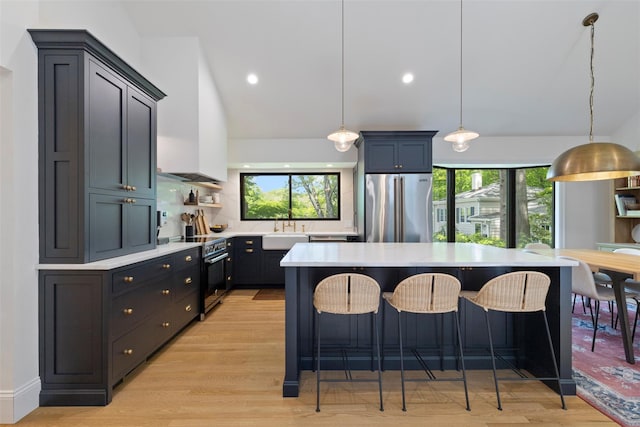 kitchen featuring high quality fridge, electric range, light countertops, a breakfast bar area, and a sink