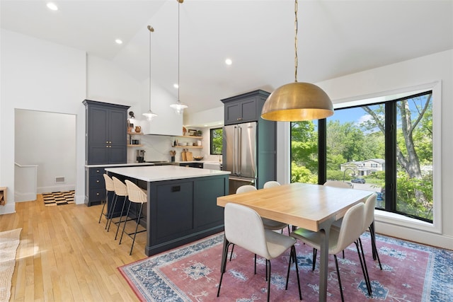 dining room with light wood finished floors, high vaulted ceiling, recessed lighting, and baseboards