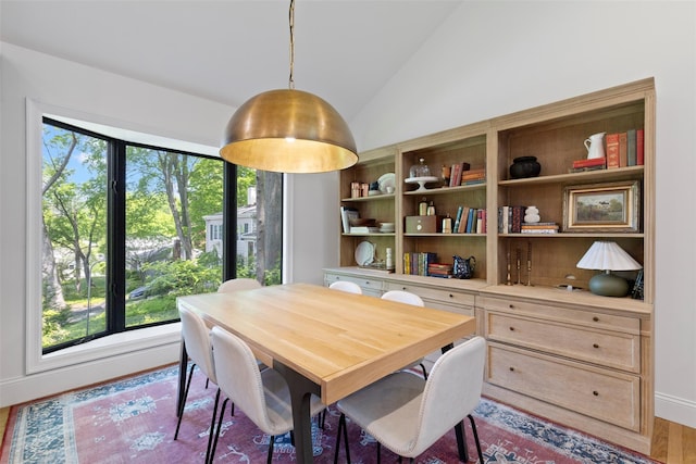 dining space featuring lofted ceiling, wood finished floors, and baseboards