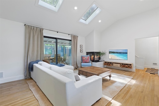 living area with a skylight, high vaulted ceiling, light wood-style floors, baseboards, and recessed lighting