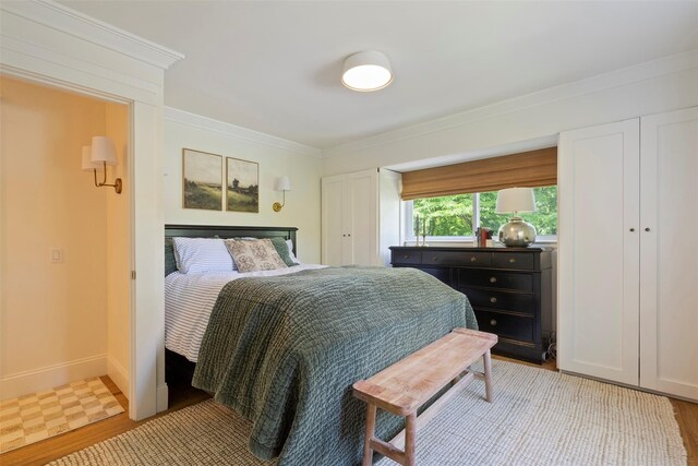 bedroom featuring crown molding, light wood-style floors, and baseboards