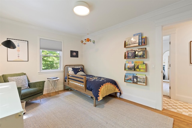 bedroom with crown molding, wood finished floors, and baseboards