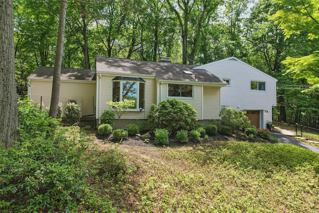 view of front of home featuring an attached garage, driveway, fence, and a shingled roof