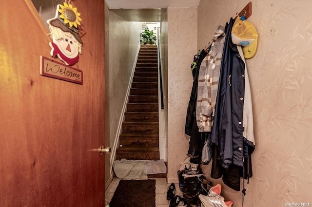 stairs with tile patterned floors and wallpapered walls