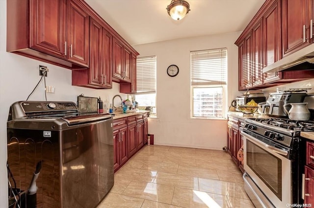 kitchen featuring light countertops, stainless steel range with gas stovetop, washer / clothes dryer, dark brown cabinets, and a sink