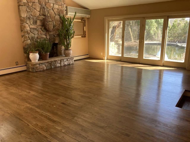 unfurnished living room with an AC wall unit, a wealth of natural light, vaulted ceiling, and a baseboard radiator