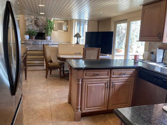 kitchen featuring light tile patterned floors, a fireplace, appliances with stainless steel finishes, and a healthy amount of sunlight