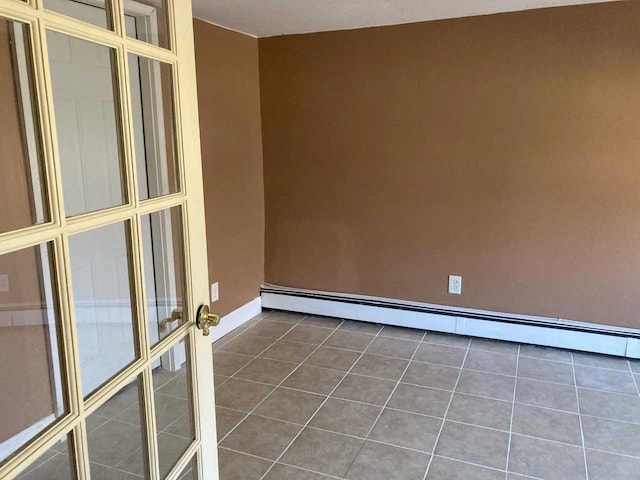 unfurnished room featuring dark tile patterned flooring, baseboard heating, and baseboards