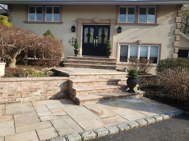 property entrance with stucco siding and french doors