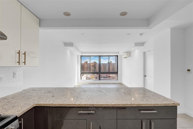 45-16 83rd St Unit E2J, Elmhurst, NY 11373 - kitchen with light stone countertops, a wall mounted air conditioner, tasteful backsplash, and a peninsula
