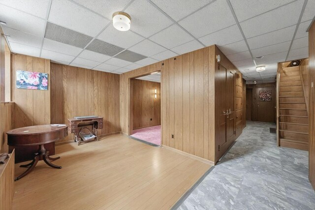 6107 Grand Ave, Maspeth, NY 11378 - hall with wood walls, a drop ceiling, stairs, wood finished floors, and baseboards